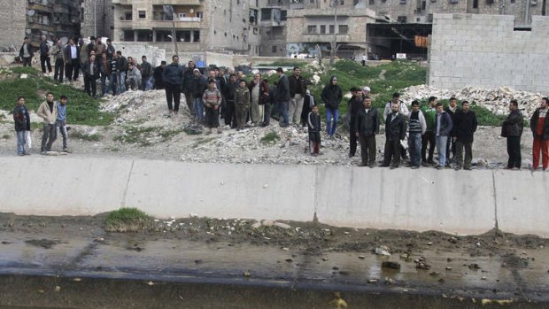 Syrian citizens gather to look at the bodies at a river in the neighborhood of Bustan al-Qasr in Aleppo, Syria.