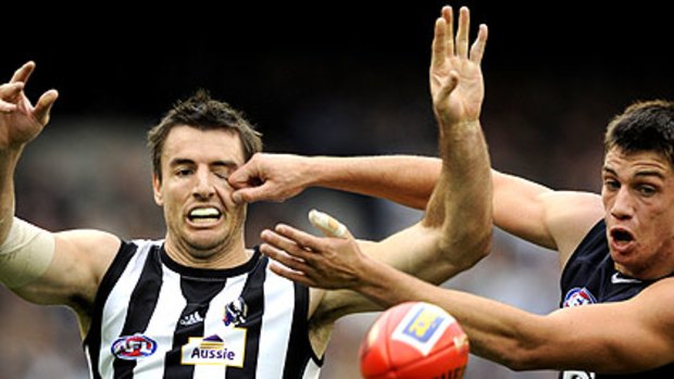 Collingwood’s Darren Jolly and Carlton’s Matthew Kreuzer lock horns in an arm wrestle for the ball at the MCG yesterday.