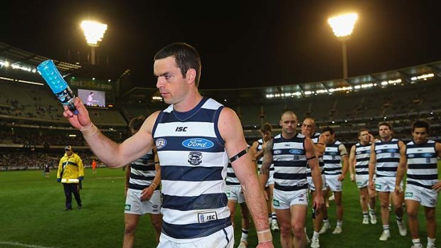 Down and out: Matthew Scarlett leads the grim-faced Cats off the MCG last night.