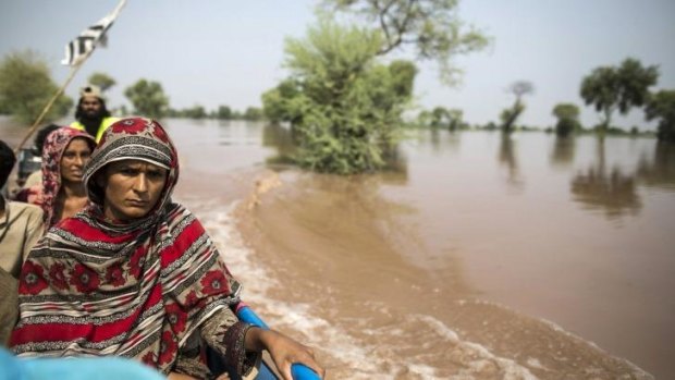 A flood victim sits on a boat while being evacuated from her flooded house following heavy rain in Jhang, Punjab province.