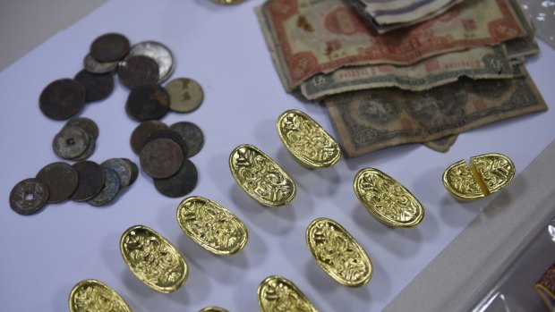 Police say they found about 100 ingots, eight Buddha statues, coins from other currencies and mobile phones when they searched Ming Zhu's hotel room. 