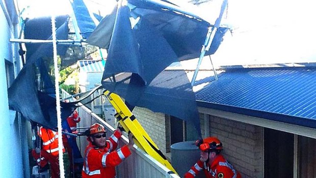 SES volunteers retrieve a trampoline from the roof of a house.
