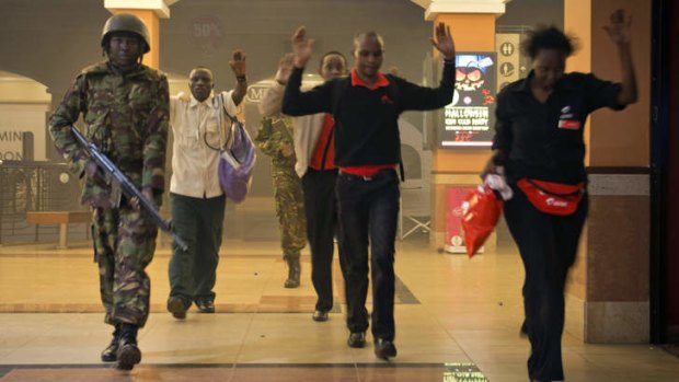 Civilians who had been hiding during a gun battle inside the Westgate mall hold their hands in the air before being searched by armed police leading them to safety.