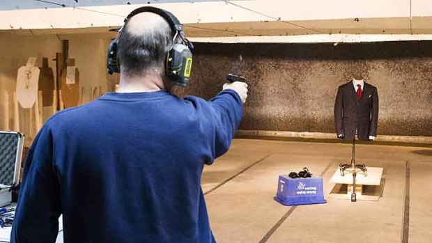 A marksman shoots a handgun at a bulletproof suit made by Garrison Bespoke tailors during a demonstration at a gun range.