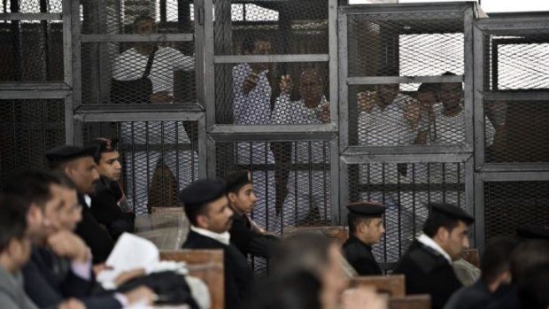 Australian journalist Peter Greste (centre) of Al-Jazeera and his colleagues stand inside the defendants' cage in a Cairo courtroom.