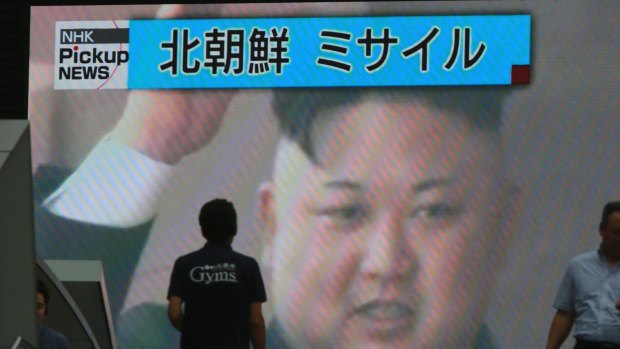 People walk in front of a TV image of North Korean leader Kim Jong-un shown on a large screen after a missile landed in the waters of Japan's economic zone.