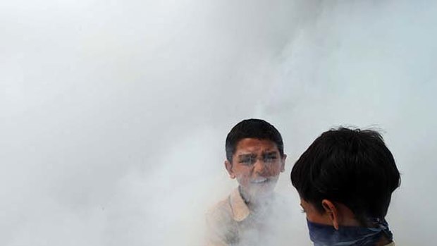 Urgency ... two boys stand in the smoke as health workers spray against diseases at a camp in Nowshera. The United Nations has confirmed the first case of cholera.