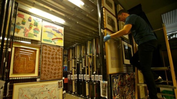 A worker installs some pieces from Artbank's collection on the racks.