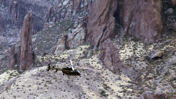Six dead ... a Maricopa County Sheriff Police helicopter flies over the Superstition Mountains searching for victims.