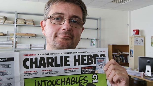 Publishing director of the satiric weekly Charlie Hebdo, Charb, displays the front page of the magazine in Paris.