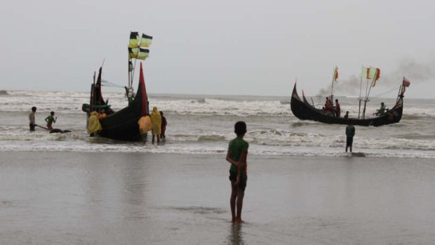 A boy watches fishing boats leave from the southern coast of Bangladesh. Rohingya are, increasing numbers, boarding people smugglers' boats like these, and meeting up with cargo ships further out to sea, which take them to Thailand, Malaysia, and Indonesia.