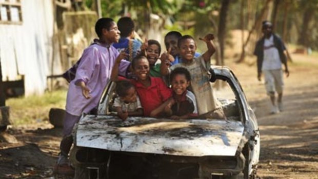 Traditional family bonds have broken down...children in Port Moresby enjoy using a car wreck as a playground.