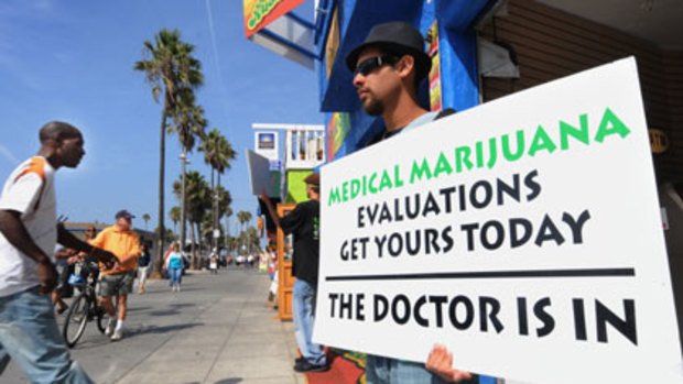 Dispensations ... a man holds a placard at a clinic at Venice Beach, Los Angeles. Critics say some doctors will prescribe marijuana for people who are not ill.