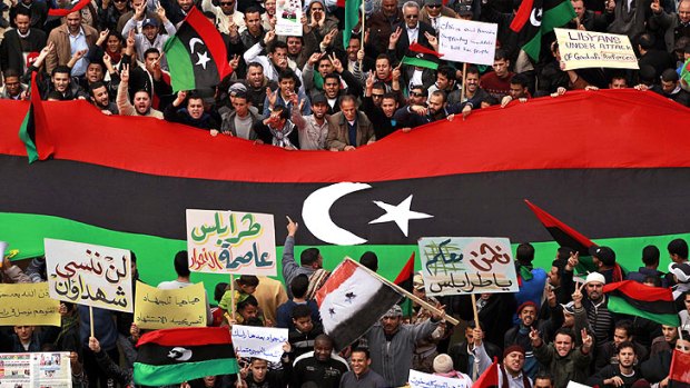 Protesters in the eastern city of Benghazi hold a large pre-Gaddafi flag.