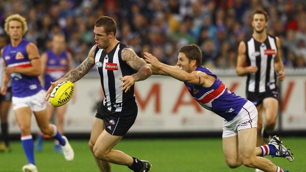 Collingwood's Dane Swan kicks the ball whilst avoiding the tackle of Matthew Boyd.