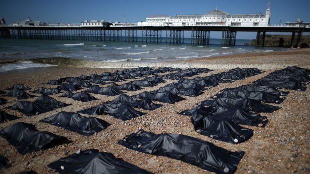 Amnesty International volunteers lie in body bags on the beach in Brighton, England. 