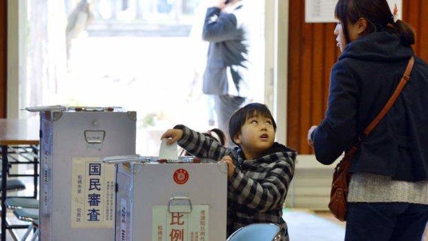 A boy helps his mother cast her vote in the general election at a polling station in Funabashi, suburban Tokyo.