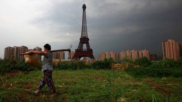 A farmer walks past a replica of the Eiffel tower at a development in Tianducheng.