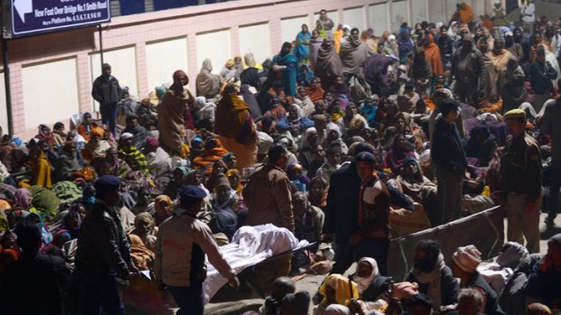 Indian authorities carry the bodies of two travellers killed in the crush.