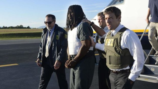 FBI agents escort Jesse L. "LJ" Matthew Jr., centre, from a plane during extradition to Charlottesville, Virginia.