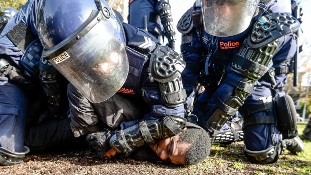 A protester was arrested by riot police after damaging an Age photographer's camera.