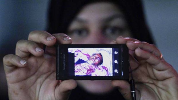 A Bahraini protester shows a pictures of a man who was injured by riot police in Manama.