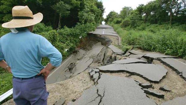A man looks at a road destroyed by an earthquake in Oshu City, Iwate Prefecture.
