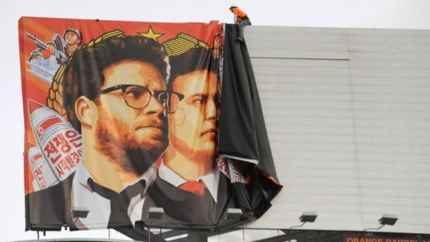 Workers remove a poster for "The Interview" from a billboard in Hollywood.