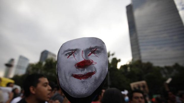 A university student holds a mock picture of opposition presidential candidate Enrique Pena Nieto during a march in demand of balance in electoral media coverage.
