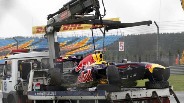Setback ... Sebastian Vettel’s Red Bull is taken away for repair.