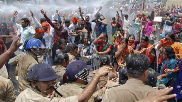 A water cannon is used to stop people protesting over the rape and murder of two girls.