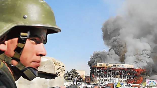 An Afghan National Army soldier keeps watch as smoke billows from a building where clashes between Taliban-linked militants and soldiers took place in Kabul.