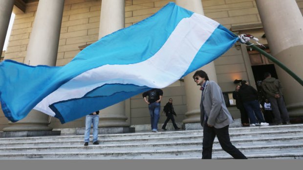 An Argentinian flag flies as people walk past the Metropolitan Cathedral in Buenos Aires, Argentina.