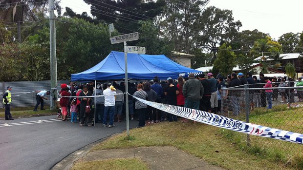 A crowd gathers at the scene of the fire at Logan this morning.