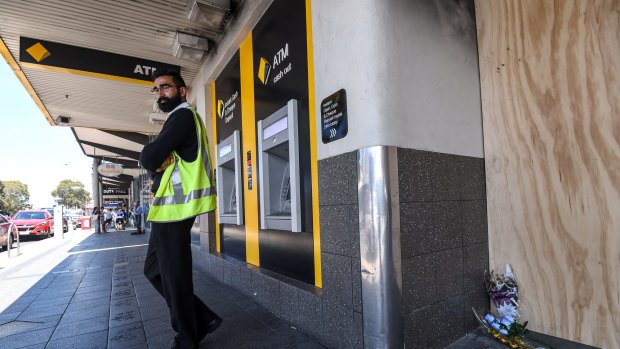 A security guard in front of the gutted Springvale Commonwealth Bank on Sunday.