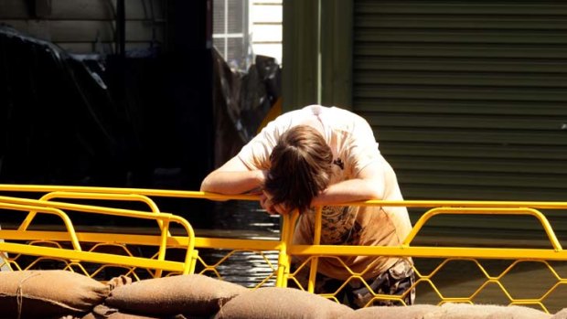 A boy takes a rest from sandbagging that appears to have failed.