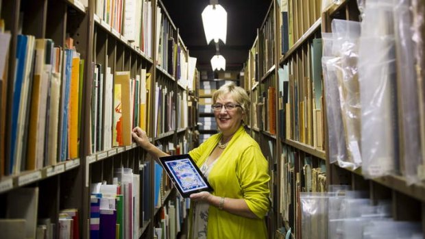 The National Library of Australia's Robyn Holmes in the music stacks holding the NLA's new iPad app called Forte which gives users access to more than 13,000 pieces of sheet music.