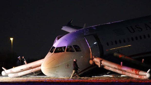 An investigator walks near a damaged US Airways jet at the end of a runway at the Philadelphia International Airport after its  nose gear collapsed on take-off.