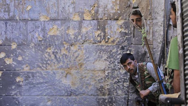 A Free Syrian Army soldier uses a mirror as he and a comrade look for government troops in Aleppo.