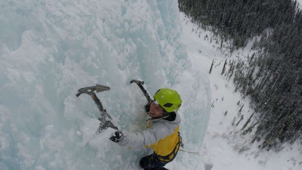 An ice climber ascends a frozen waterfall in the Canadian Rocky Mountains.