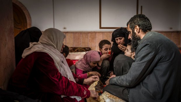 Younes Omar and his family, who reportedly escaped one of the last contested areas of Raqqa, break bread at a mosque  being used as a reception centre  on the outskirts of  the city.