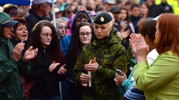Candlelight vigil: A Canadian soldier mourns the three dead Mounties in Moncton.