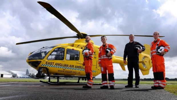 East Anglian Air Ambulance Crew members stand alongside their helicopter at Cambridge Airport, north of London.