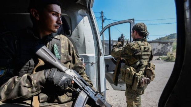 Pro-Russian rebels stand guard at a vehicle used for transportation of mobile military groups in the town of Donetsk, eastern Ukraine.