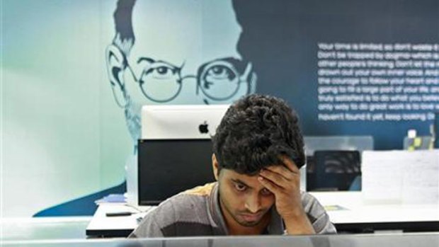 An employee works away against a backdrop of Apple co-founder, the late Steve Jobs.