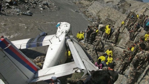 Nepalese onlookers and rescuers stand near the wreckage of the Nepal Airlines Twin Otter aircraft.