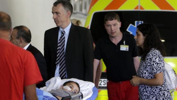 Ashya King, a five-year-old British boy with a brain tumour, lies on a stretcher as he arrives with his parents Brett (3rd from right) and Naghemeh King (right) at Motol hospital in Prague. 
