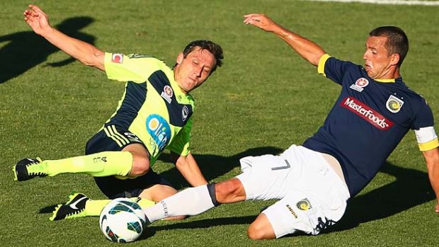 Victory's Mark Milligan challenges John Hutchinson of the Mariners during Saturday's A-League match.