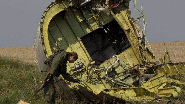 Crash investigators declare it a priority to secure crash site: A pro-Russian rebel examines the MH17 wreckage.