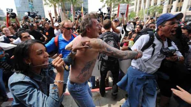 Plainclothes police remove a man with Nazi tattoos after he was beaten by an angry crowd before a neo-Nazi group held a rally in front of the Los Angeles City Hall.